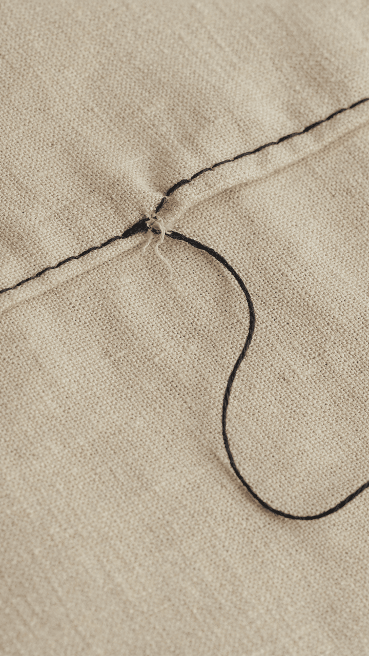 A single loose thread beginning to unravel from a stitched fabric.