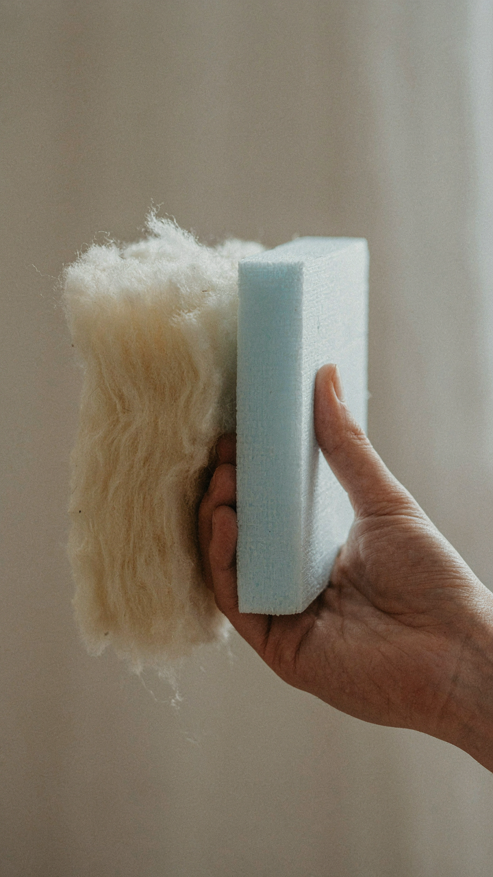 A hand holds two different insulation materials.