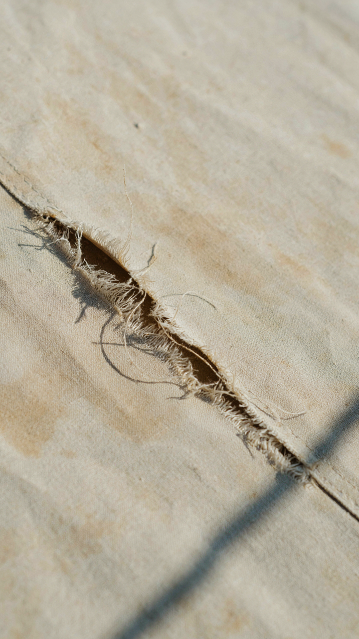 Close-up of sun-damaged, frayed cotton canvas fabric on an old outdoor tent.