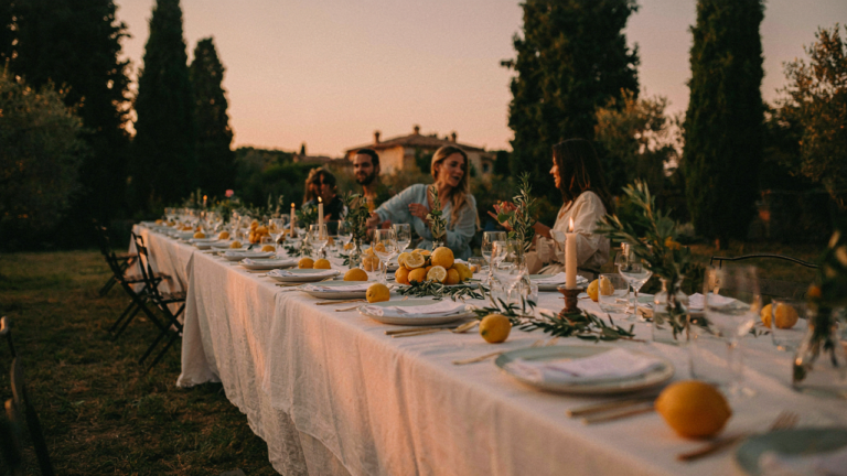 An outdoor Mediterranean garden party setting with lemons, olive branches, and white linens.