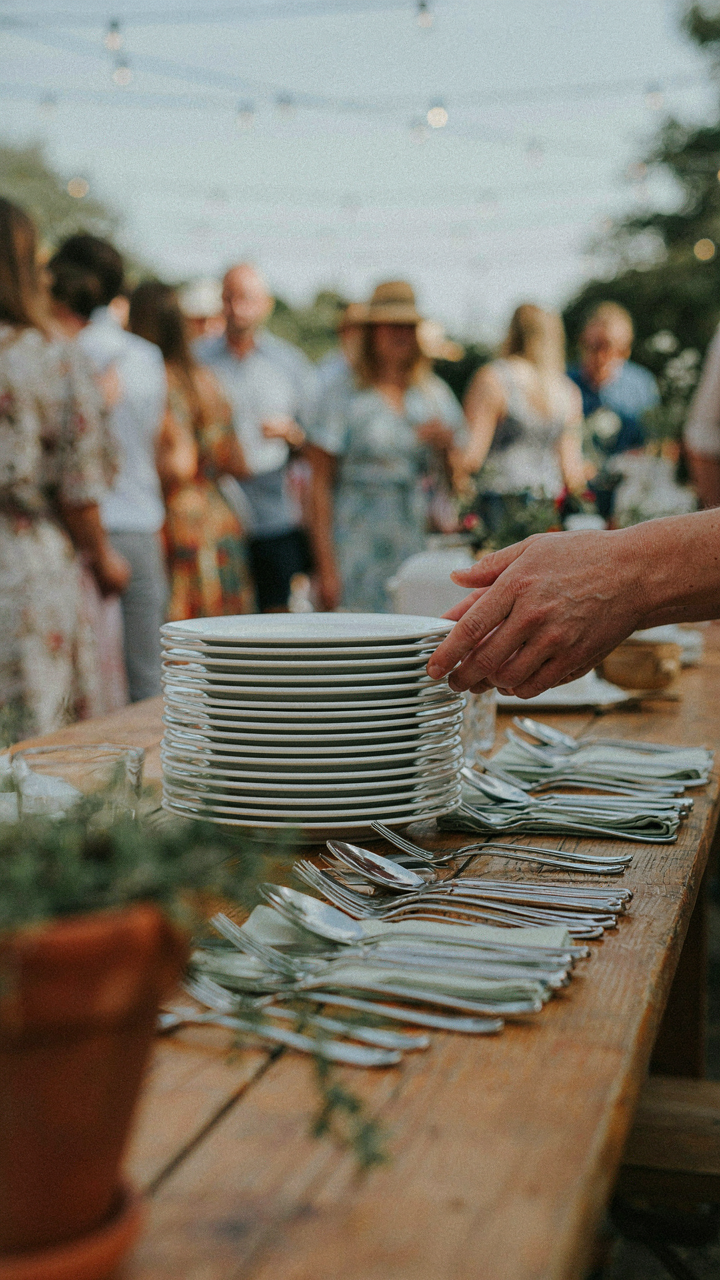 Clean plates and silverware are neatly arranged at the start of a serving line.