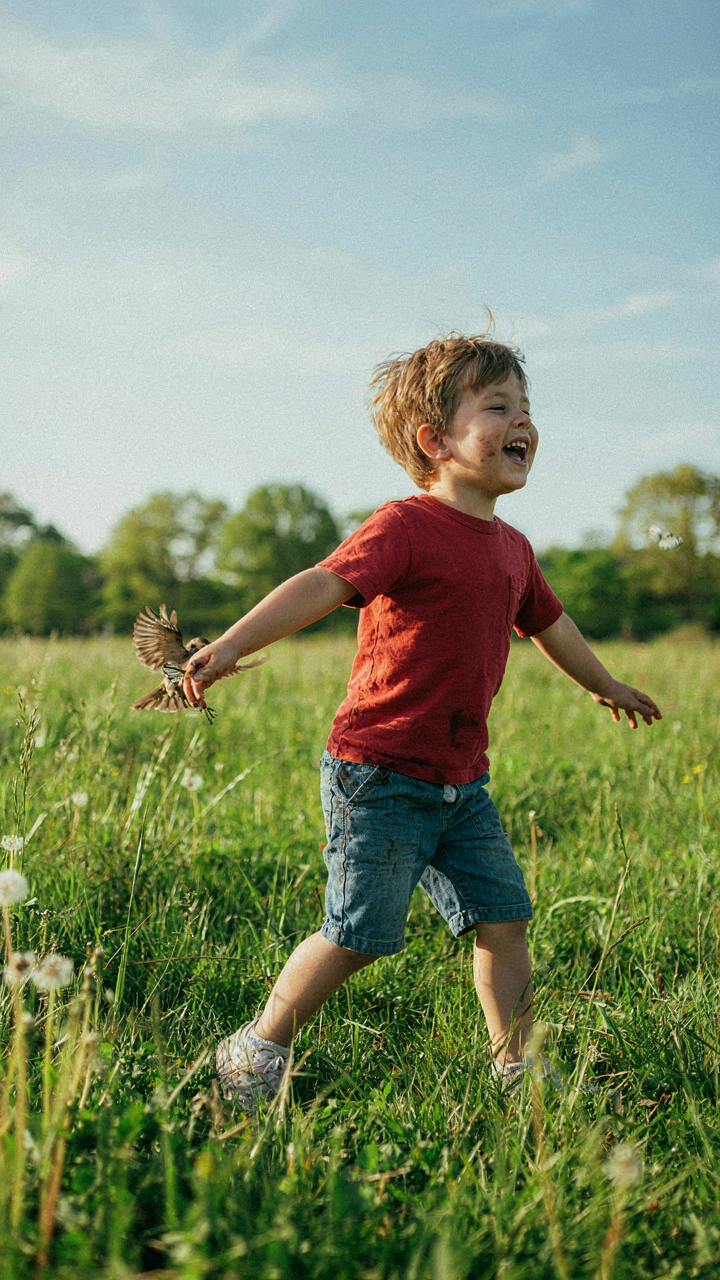 A child playing happily in a grassy field with dirty hands.