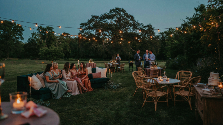 An elegant outdoor party layout with various seating and people mingling.