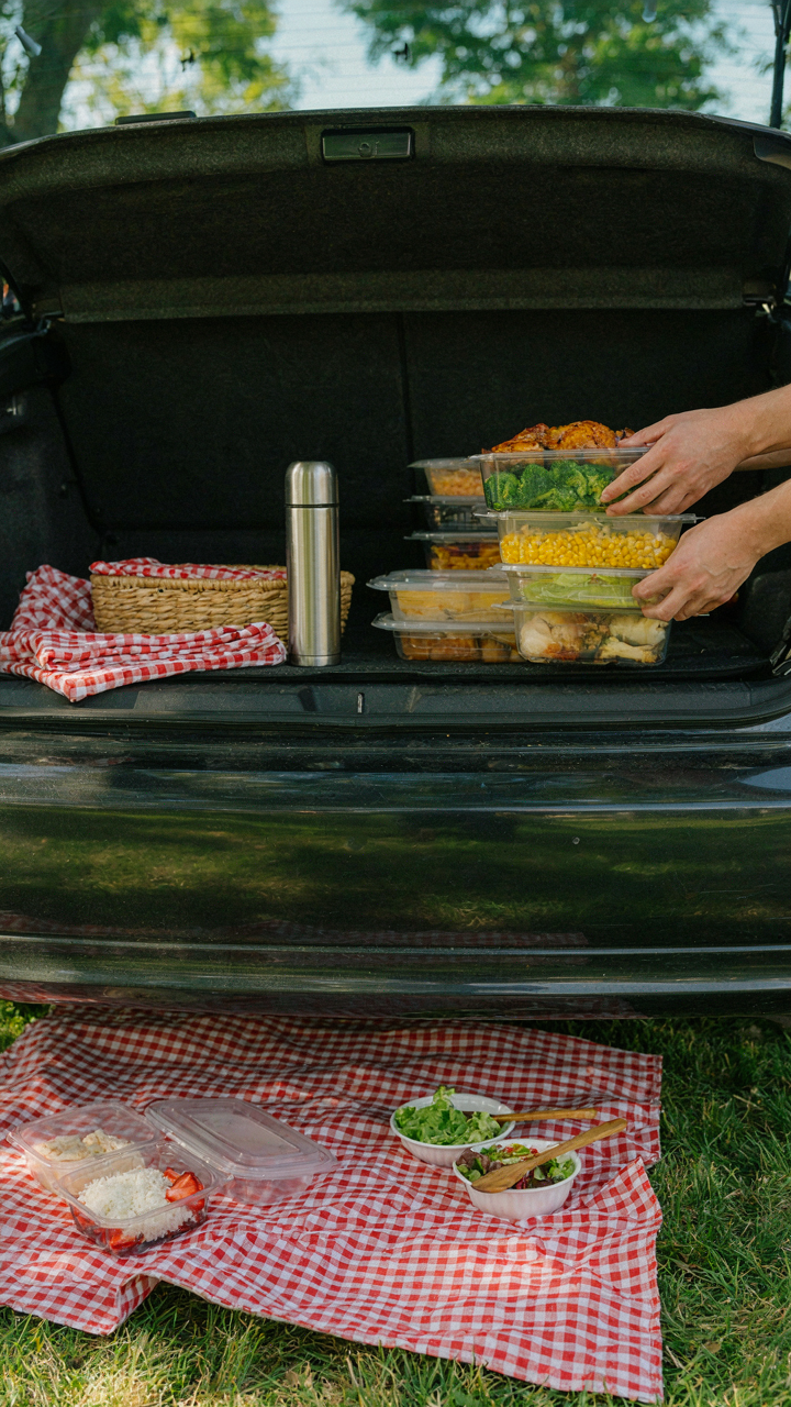 Sturdy, well-packed food containers being carefully unloaded from a car trunk.