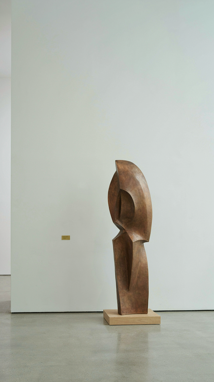 A single sculpture stands prominently in a clean, empty art gallery space.