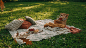 A colorful picnic blanket is spread out with many soft pillows and layered fabrics.
