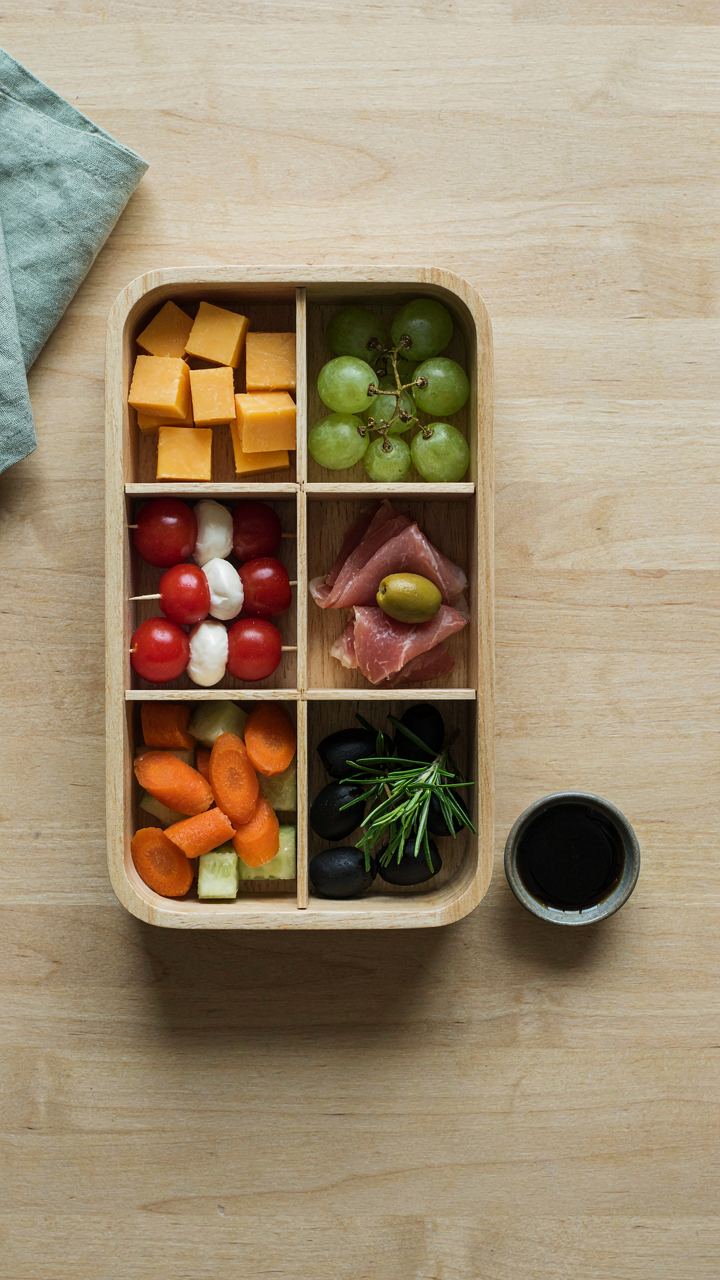 A bento box holds different finger foods for a convenient picnic.