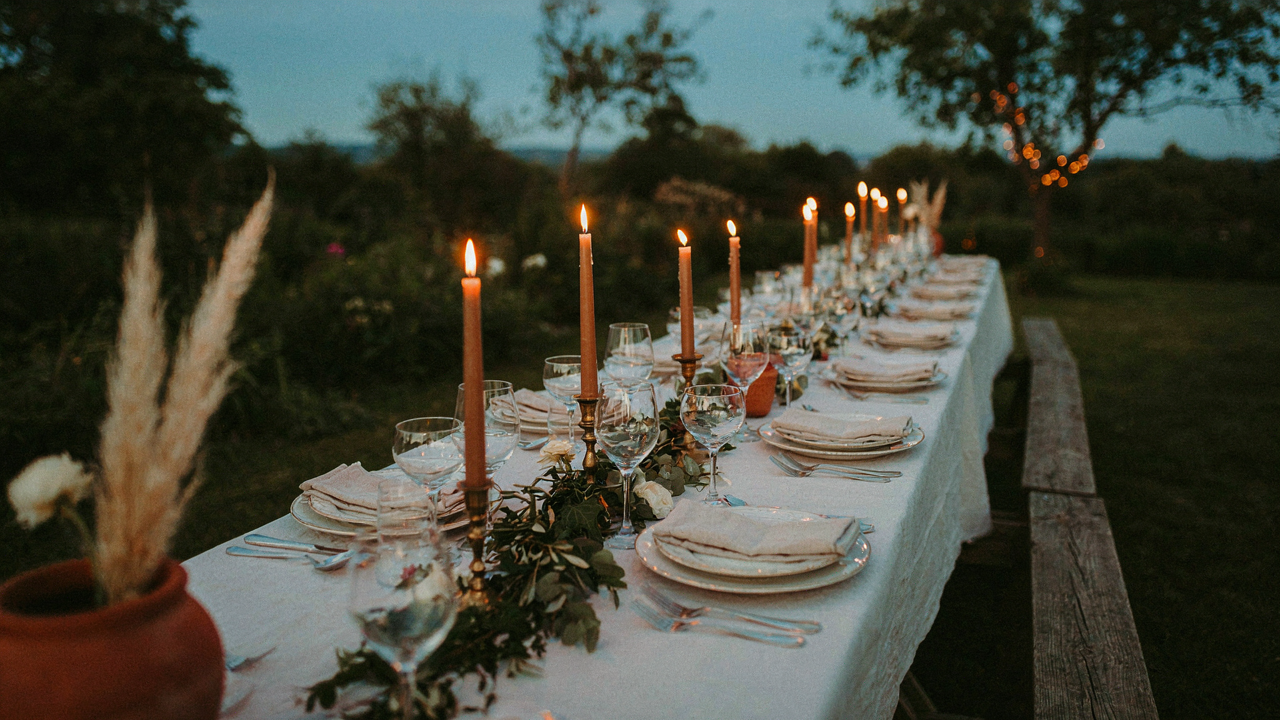 A beautiful outdoor picnic table set for a formal dinner party.