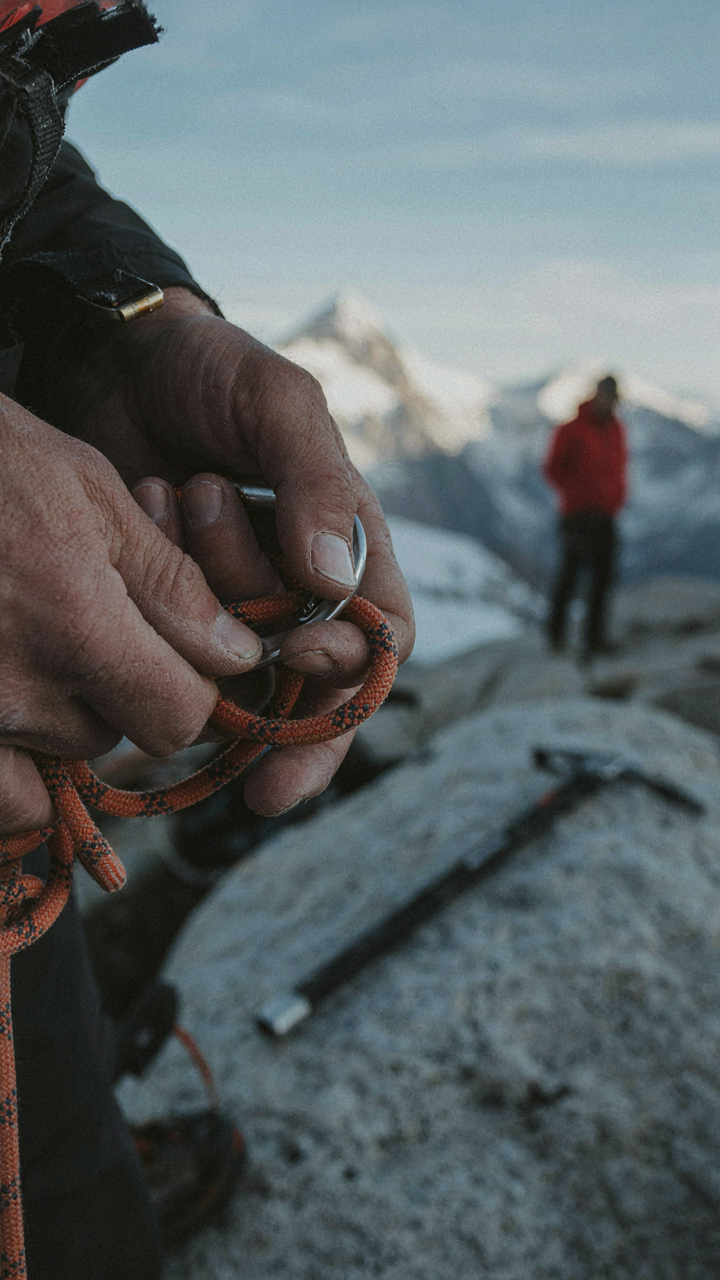A climber carefully checks their gear before climbing a mountain.