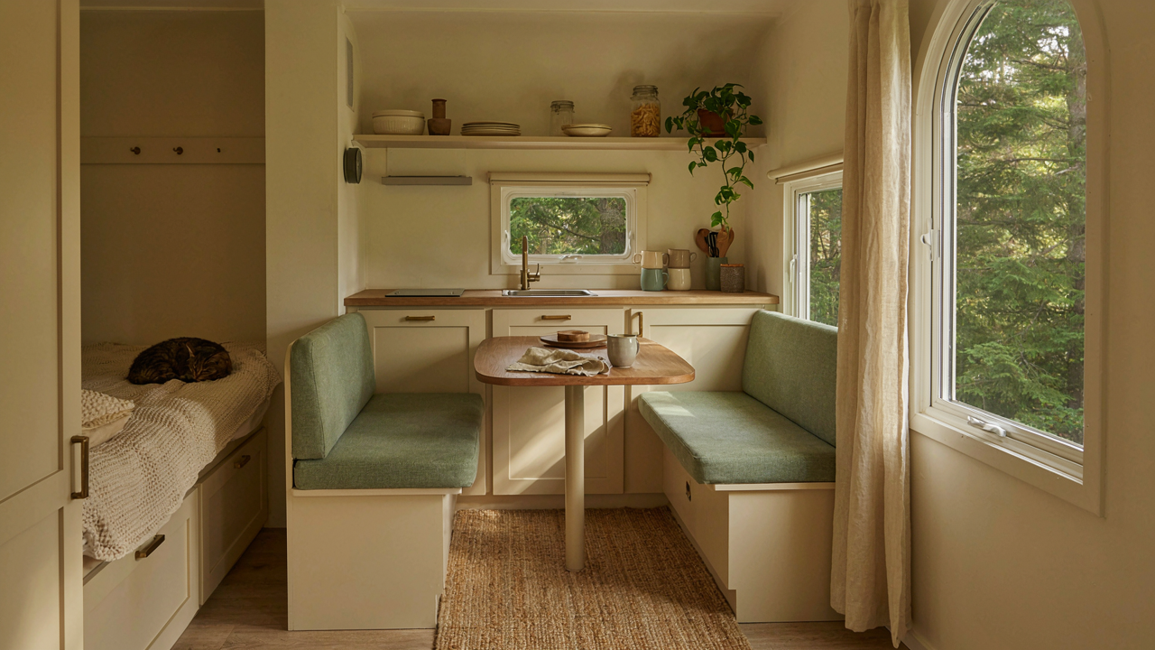 A warm, renovated pop up camper interior with smart storage and a small table.