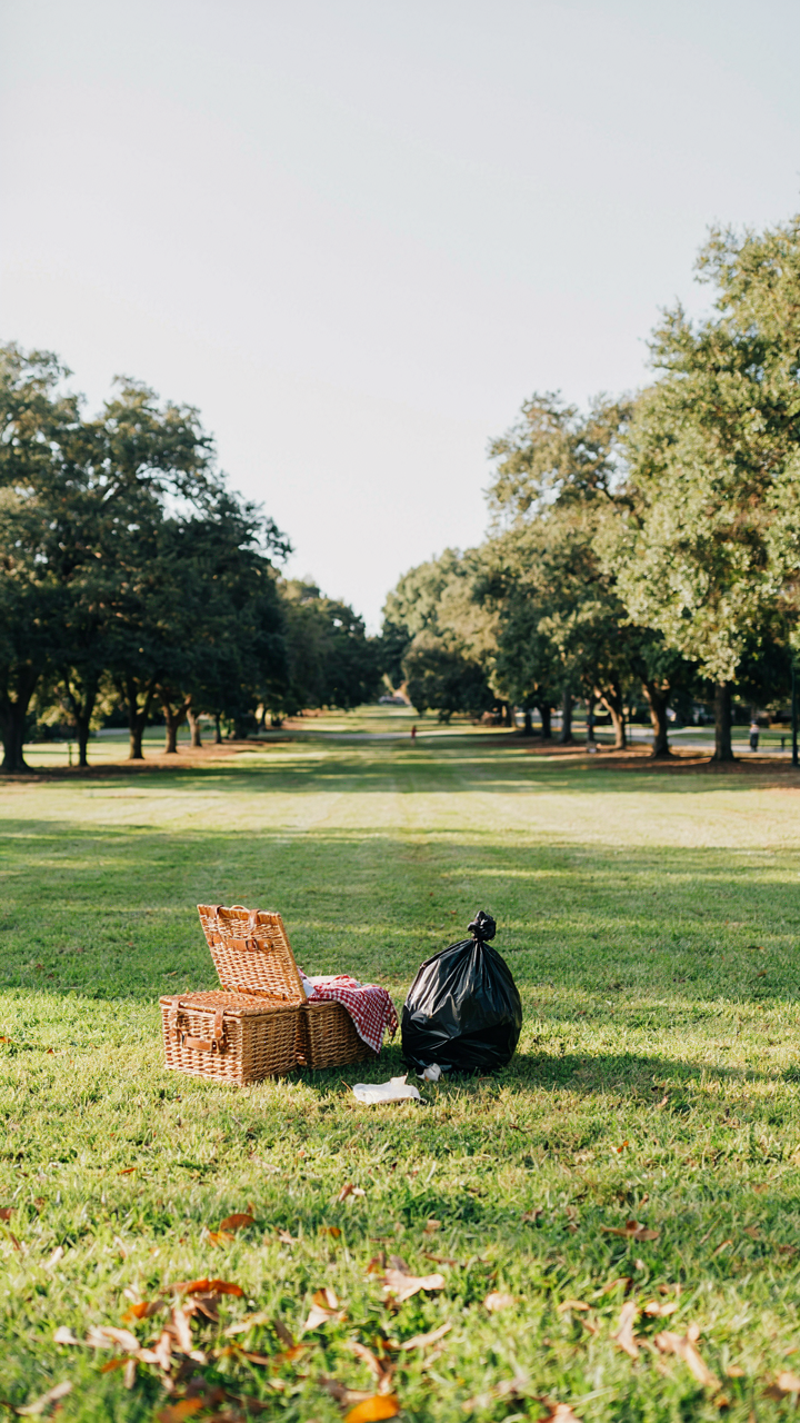 A neatly packed trash bag and clean picnic baskets in a park.