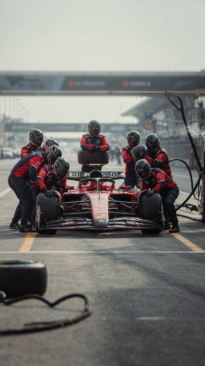A Formula 1 pit crew quickly changes tires on a race car.