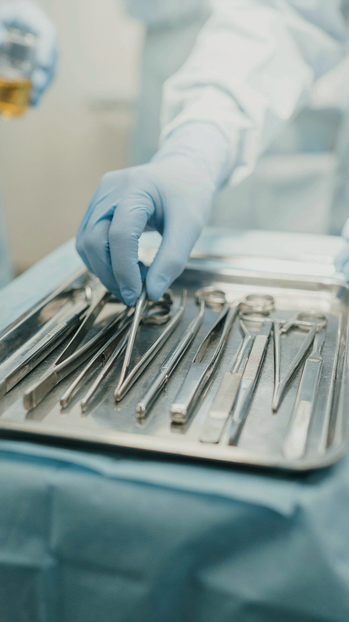 A surgeon's hands carefully arrange instruments on a sterile tray.