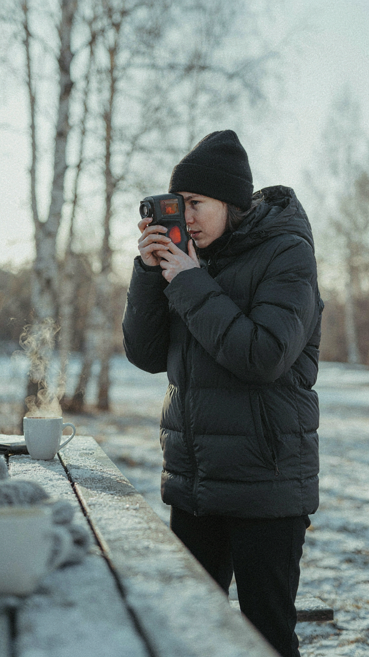 A person uses a thermal camera to see the heat from a coffee mug outside.