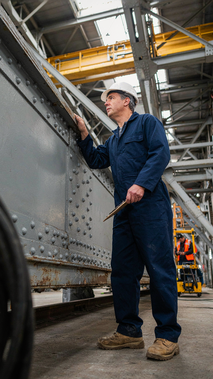 An engineer inspects a bridge's support beams for stress points.