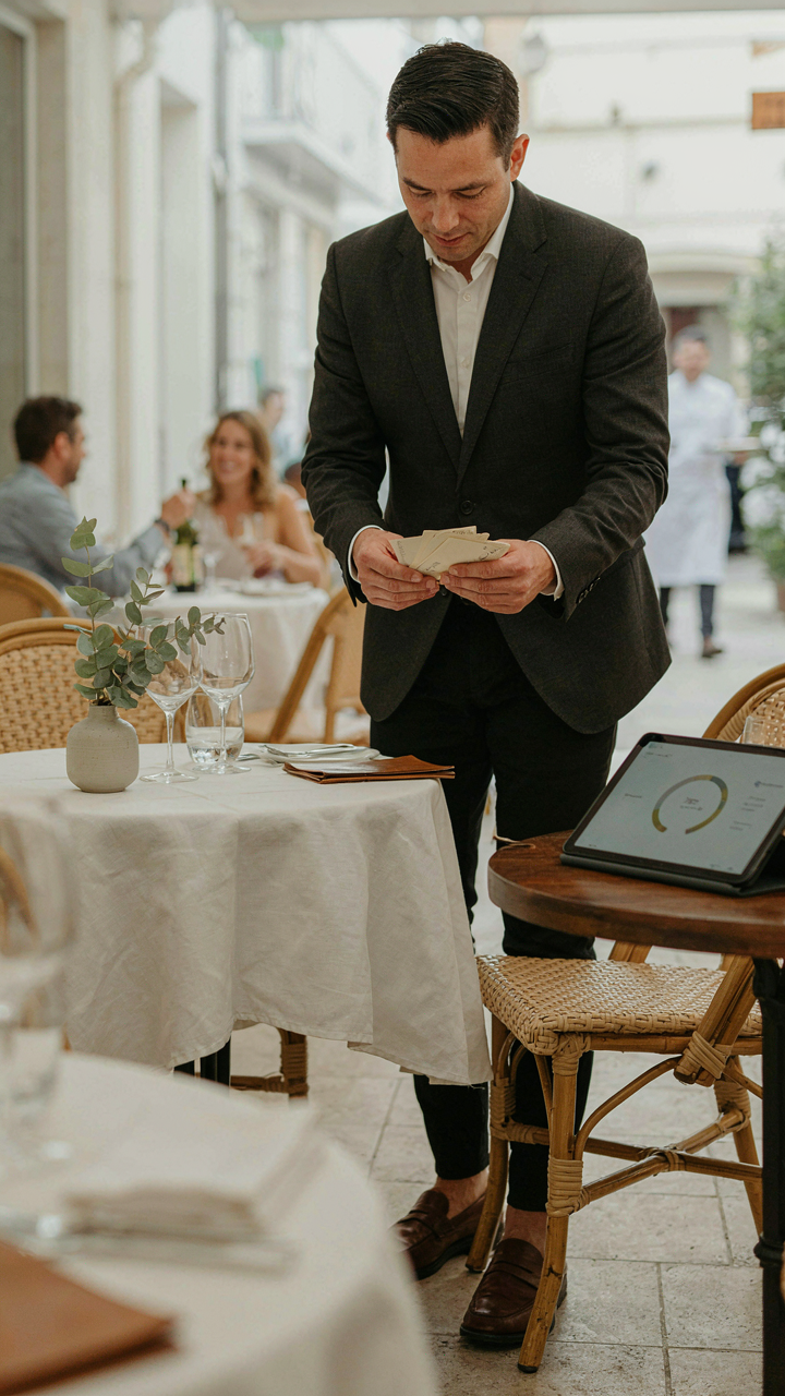 A manager reviews guest feedback on digital tablets in an outdoor setting.