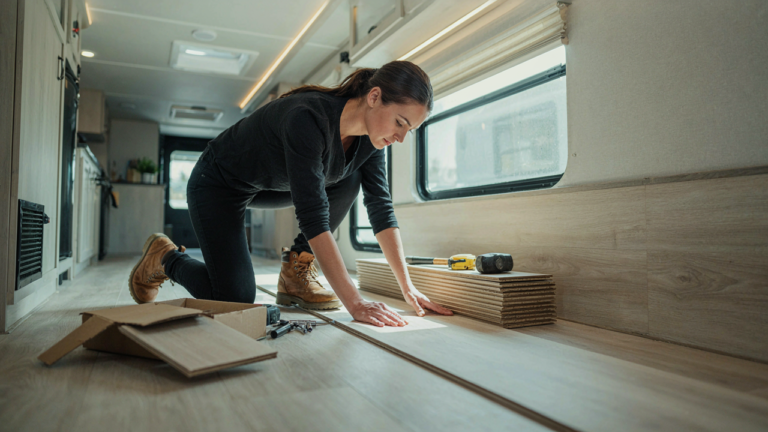 A person installs new vinyl plank flooring inside a modern RV.