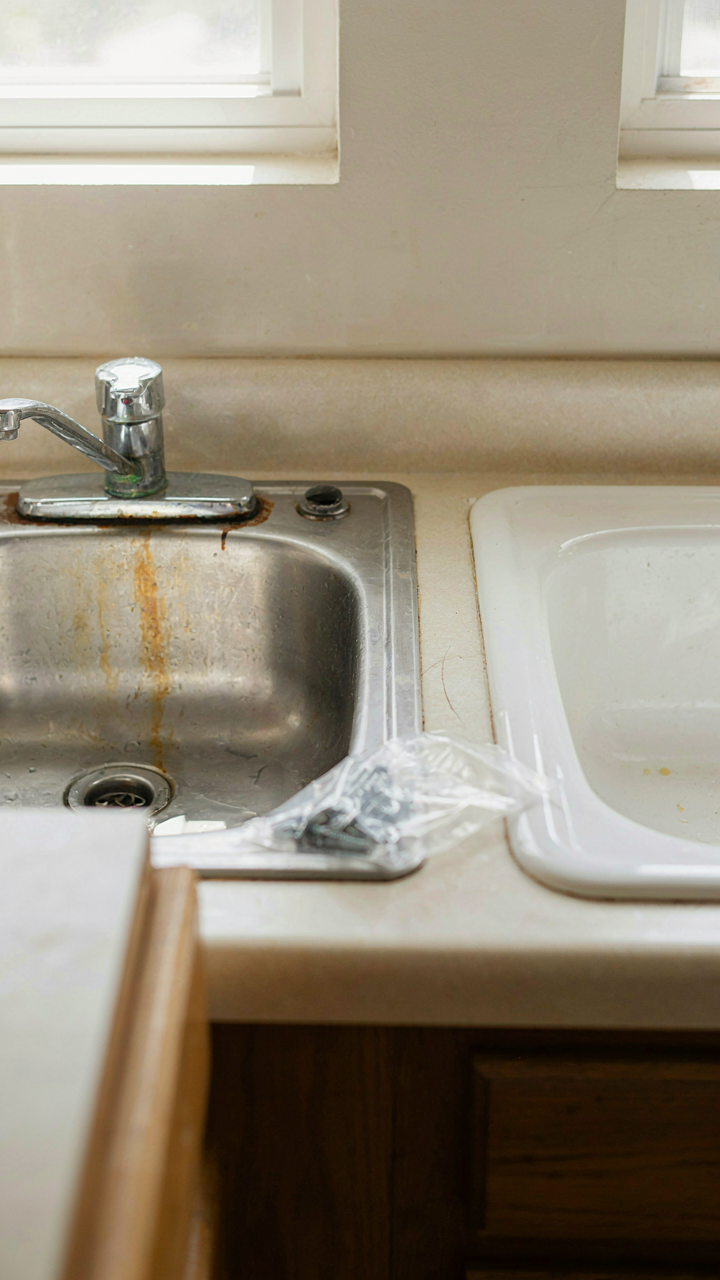 A leaky old RV sink sits next to a shiny new replacement.