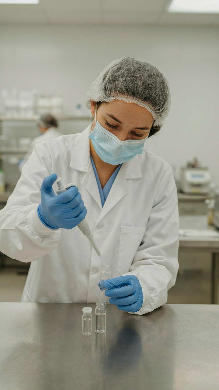 A scientist in a lab transfers liquid between vials.