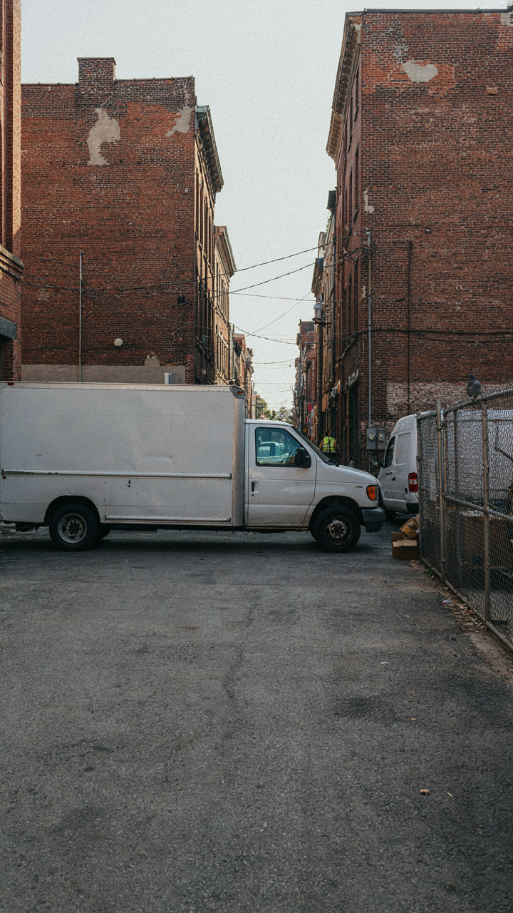 A plain gray delivery truck parked inconspicuously in a city alley.