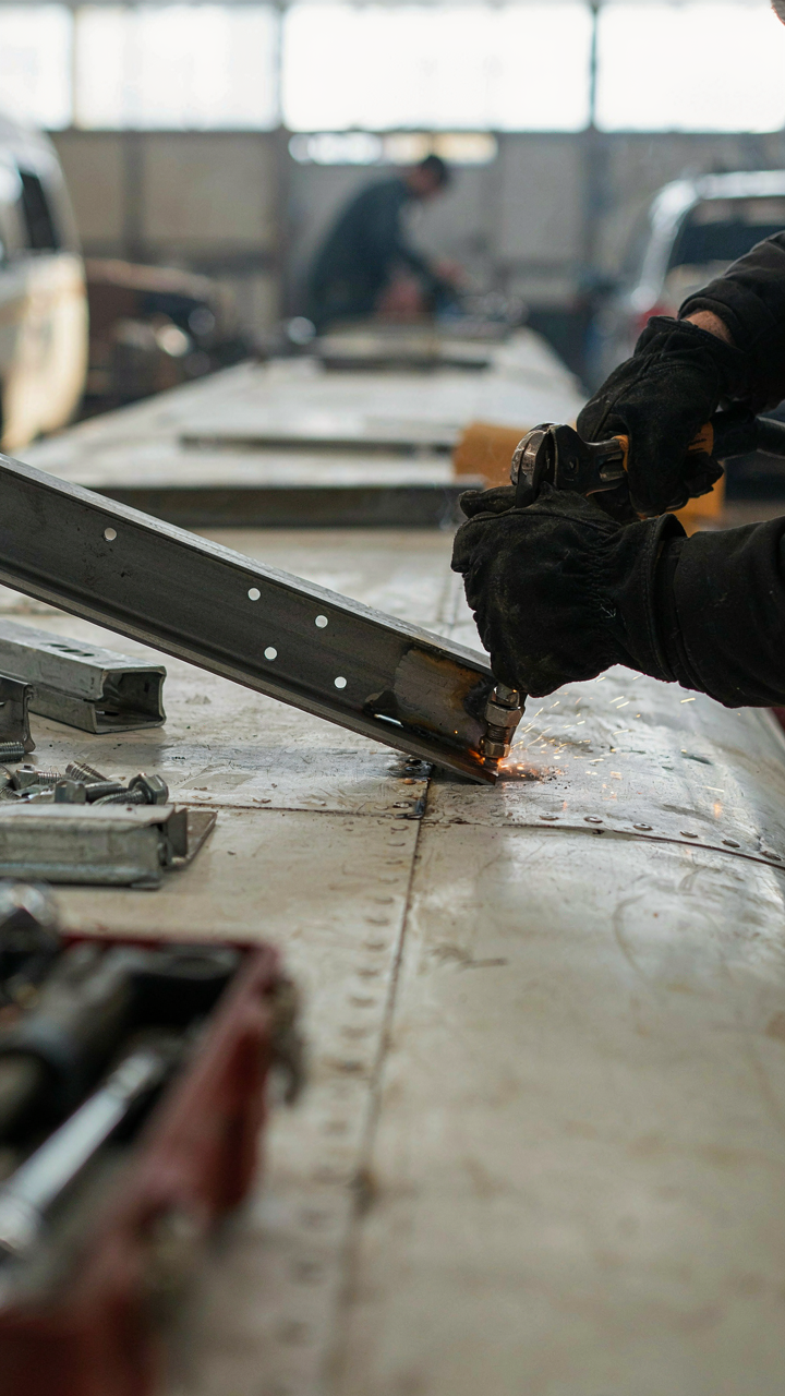 A skoolie roof is being reinforced with metal beams and welded supports.