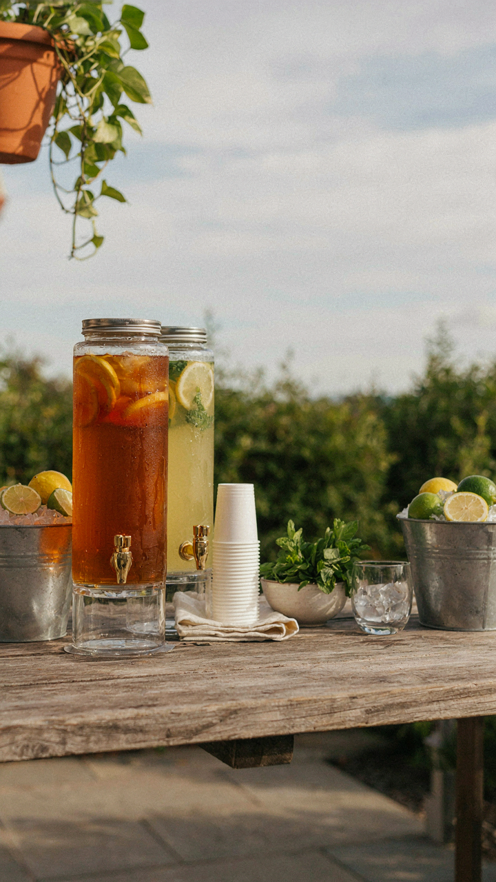 An outdoor drink station holds dispensers of iced tea and lemonade for a Labor Day cookout.