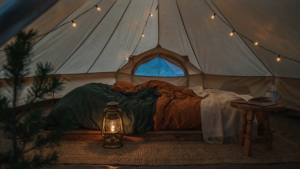 A warm tent interior at dusk with string lights and a small lantern.