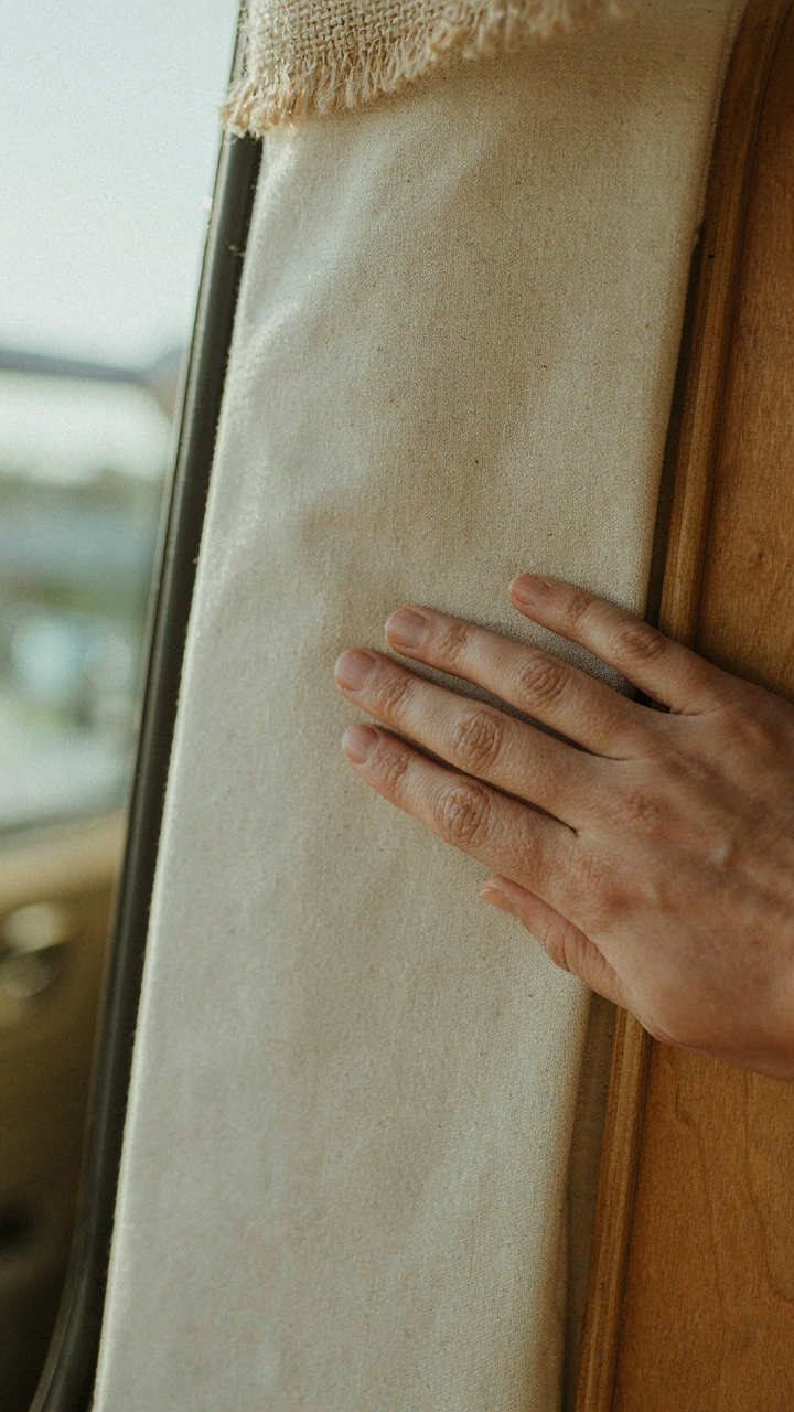 A hand touching a textured cotton canvas wall in a van, surrounded by natural materials.