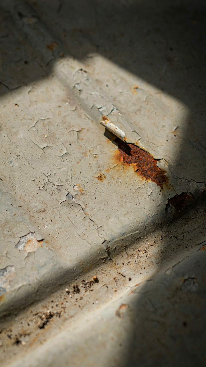 Close-up of rusted metal on a van floor with peeling paint.