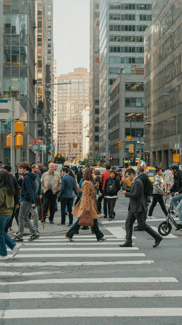Many people walk across a busy street at a crosswalk.