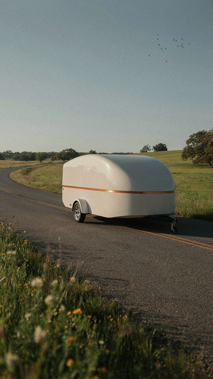 A sleek, aerodynamic lightweight camper trailer moves fast on a highway.