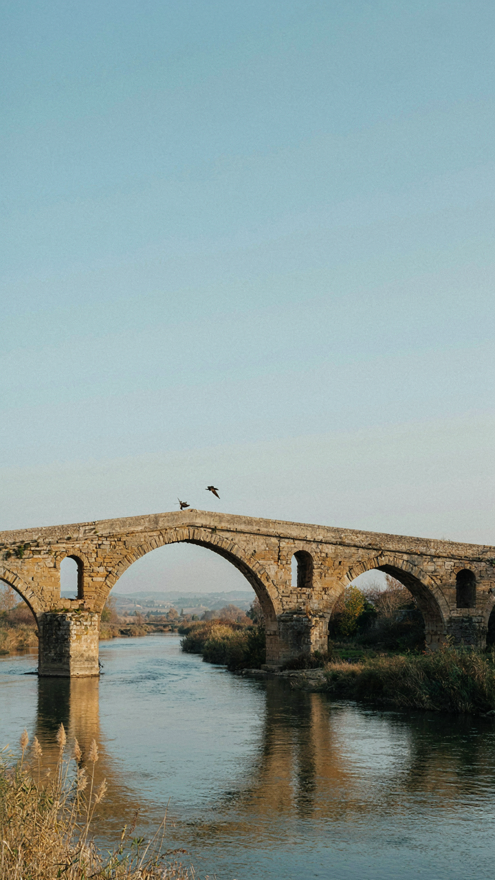 An ancient stone arch bridge with many extra support arches built into its design.