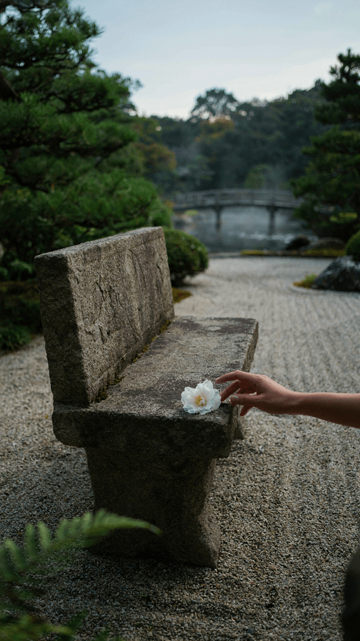 A hand touches a smooth stone bench in a serene moon garden.