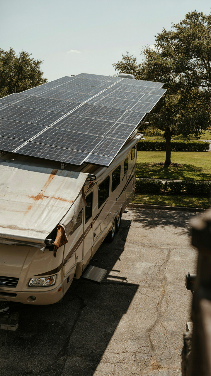 New solar panels on an RV roof next to an old, faded awning.