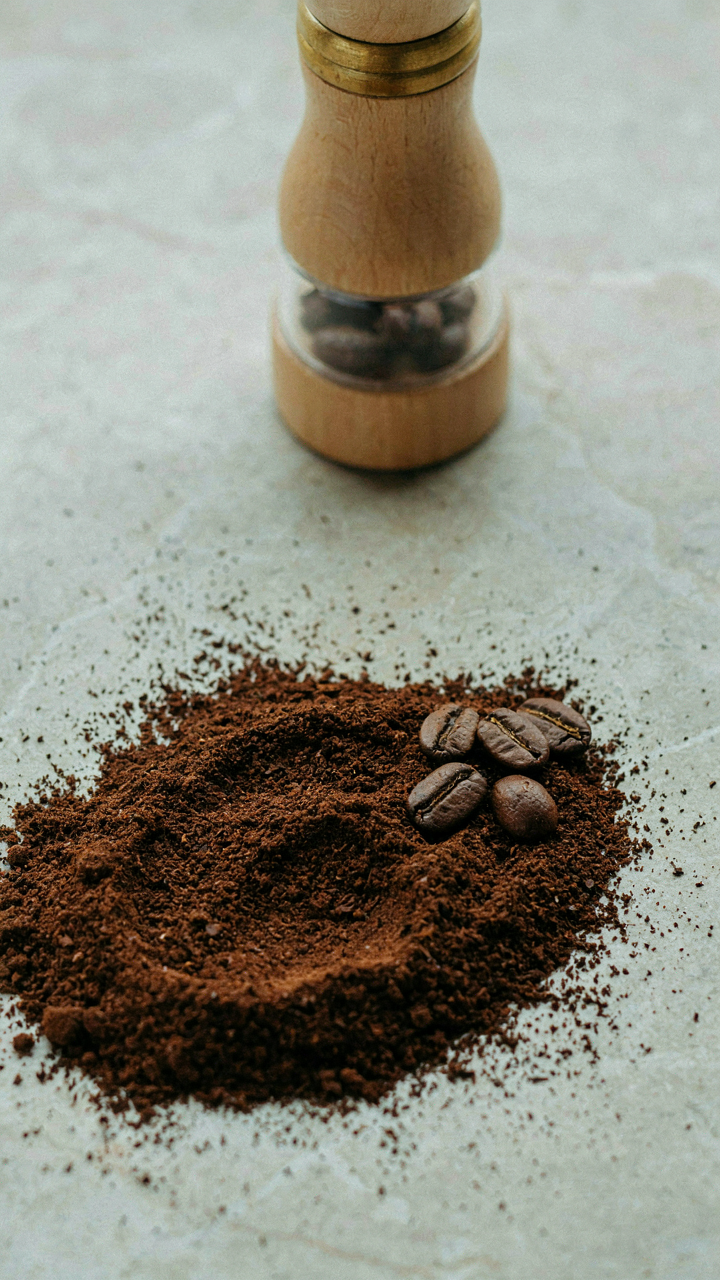 Finely ground coffee powder is next to whole coffee beans.