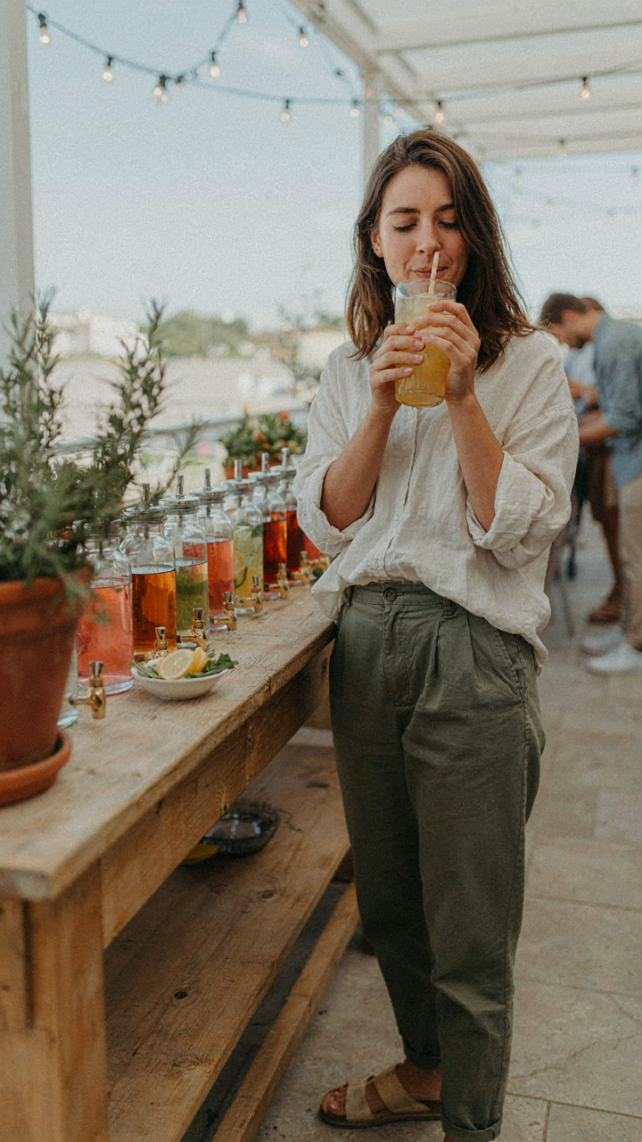 A person happily drinks from a glass at a self serve drink bar.