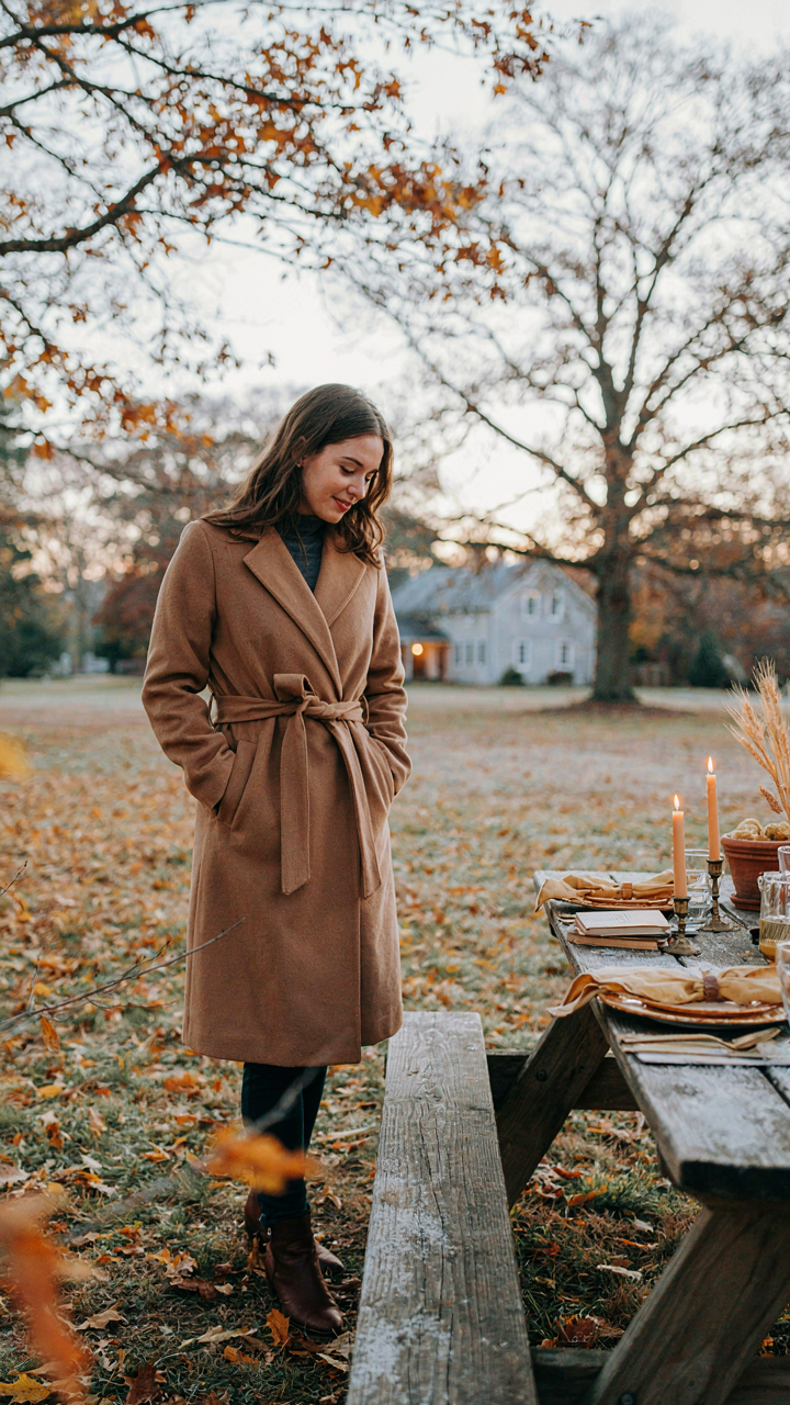 A person stands bundled in a coat, looking at a cold, empty picnic table outdoors.