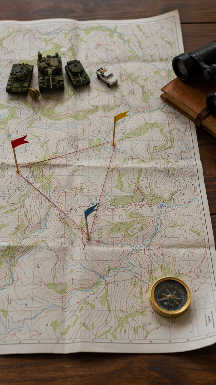 A military map with small vehicles shows supply routes and asset locations.