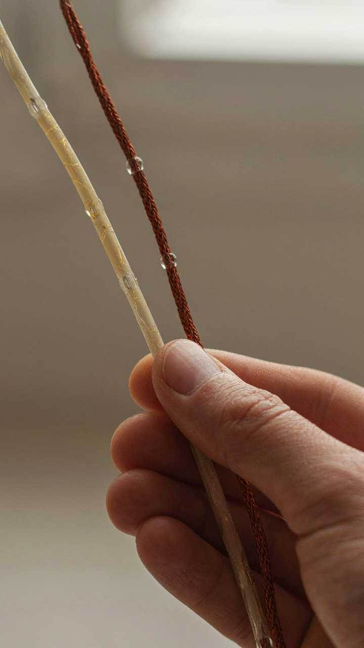 A hand holds cracked plastic string light wire next to strong copper wire.