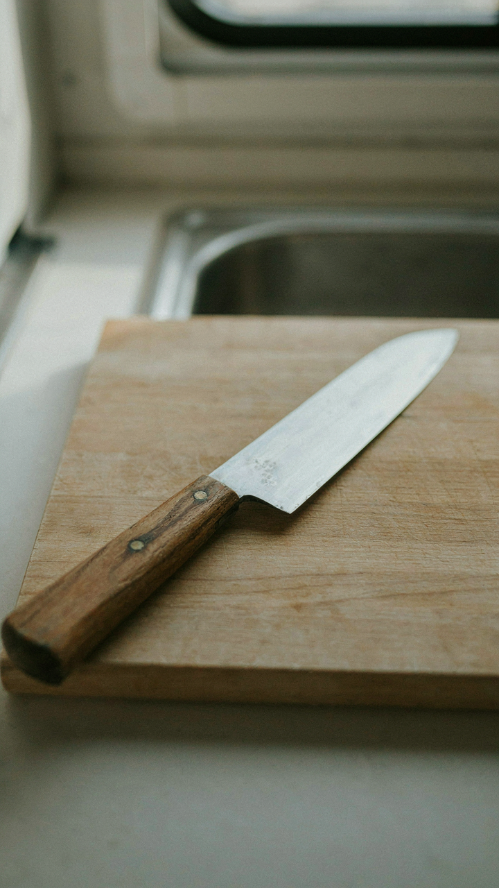 A single, well-used chef's knife on a cutting board in an RV kitchen.