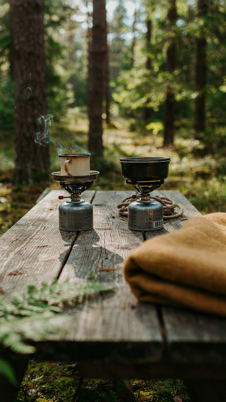 Two small camping stoves are side-by-side, one running, one ready as a backup.