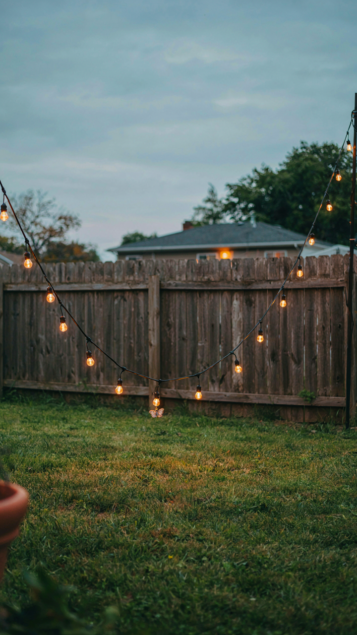 A poorly hung string of outdoor lights sagging with visible tension on a thin wire.