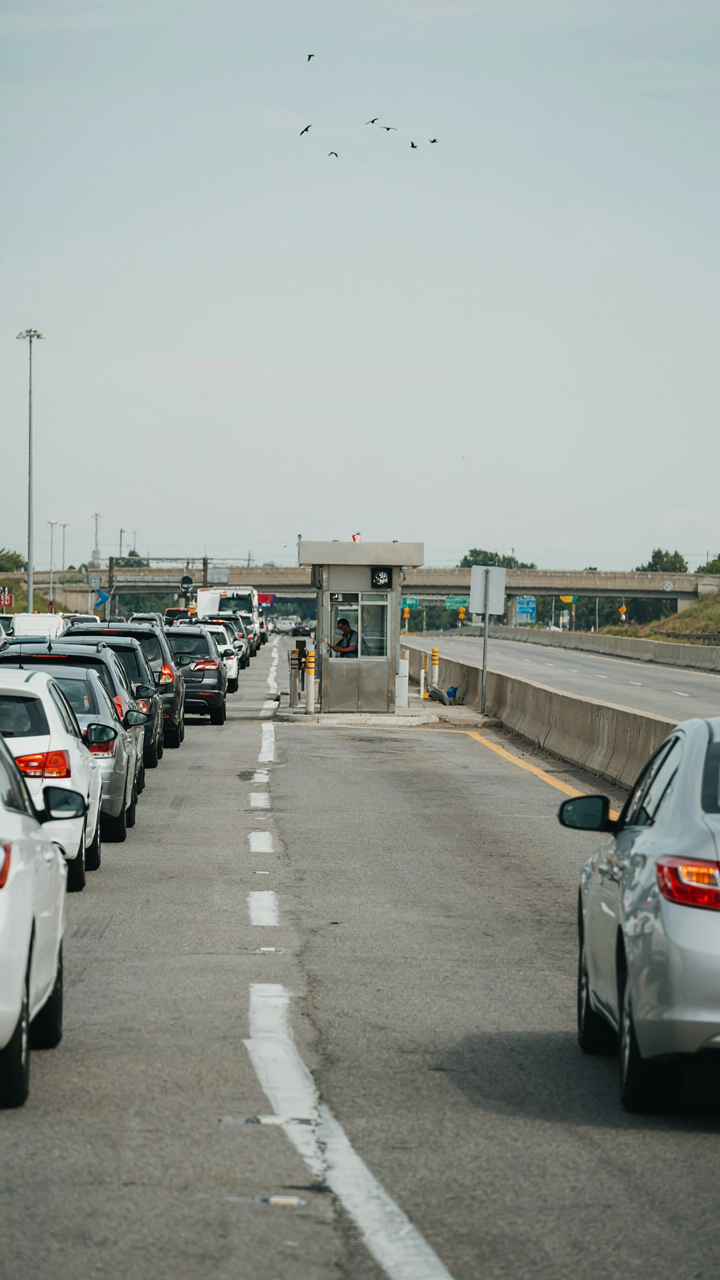 Cars are stuck in a bottleneck at a toll booth on a busy highway.