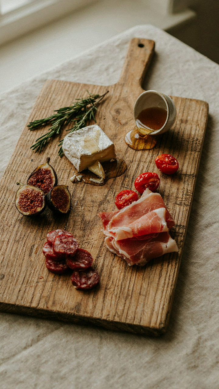 A charcuterie board with wilting fruit and sweating cheese, showing molecular chaos.