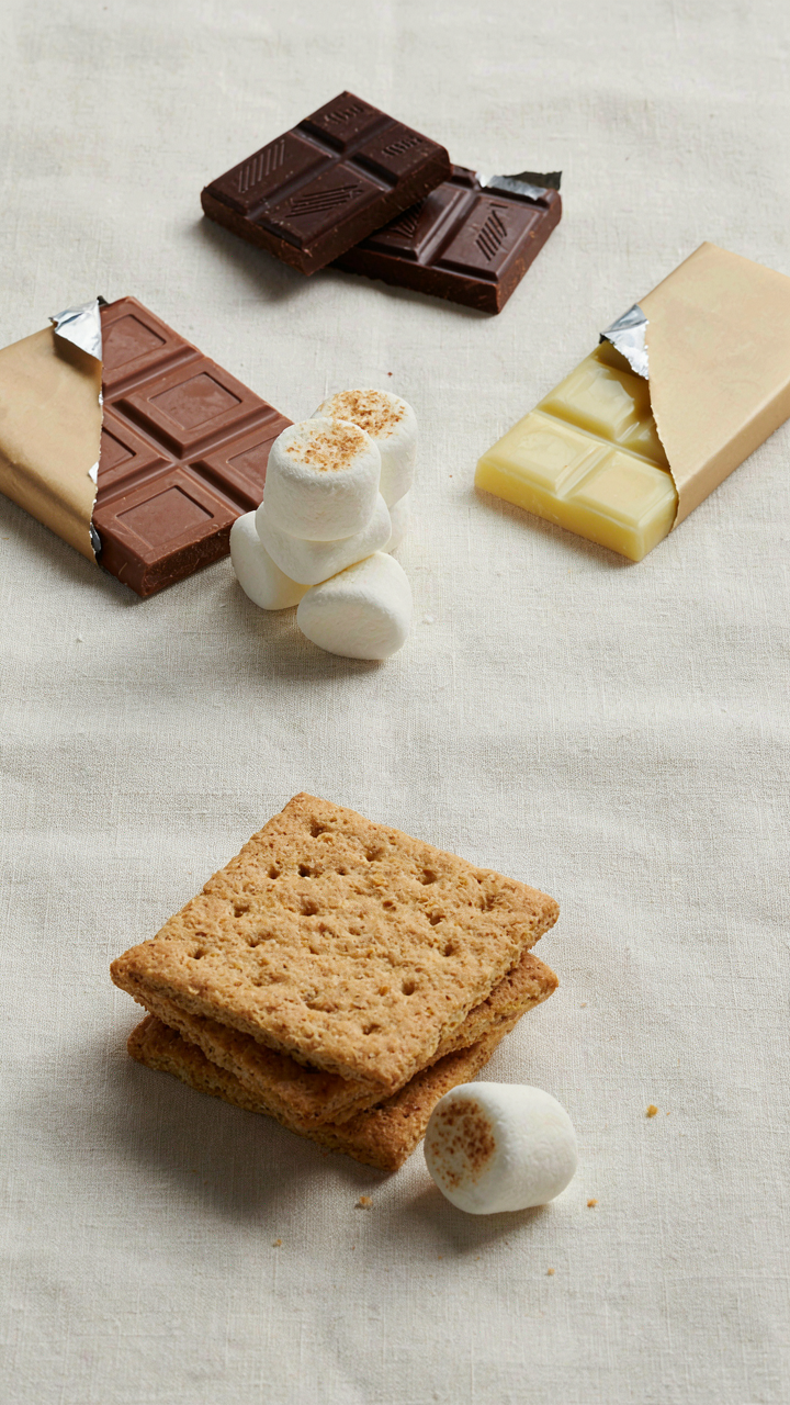 Three types of chocolate and marshmallows on a small s'mores display.