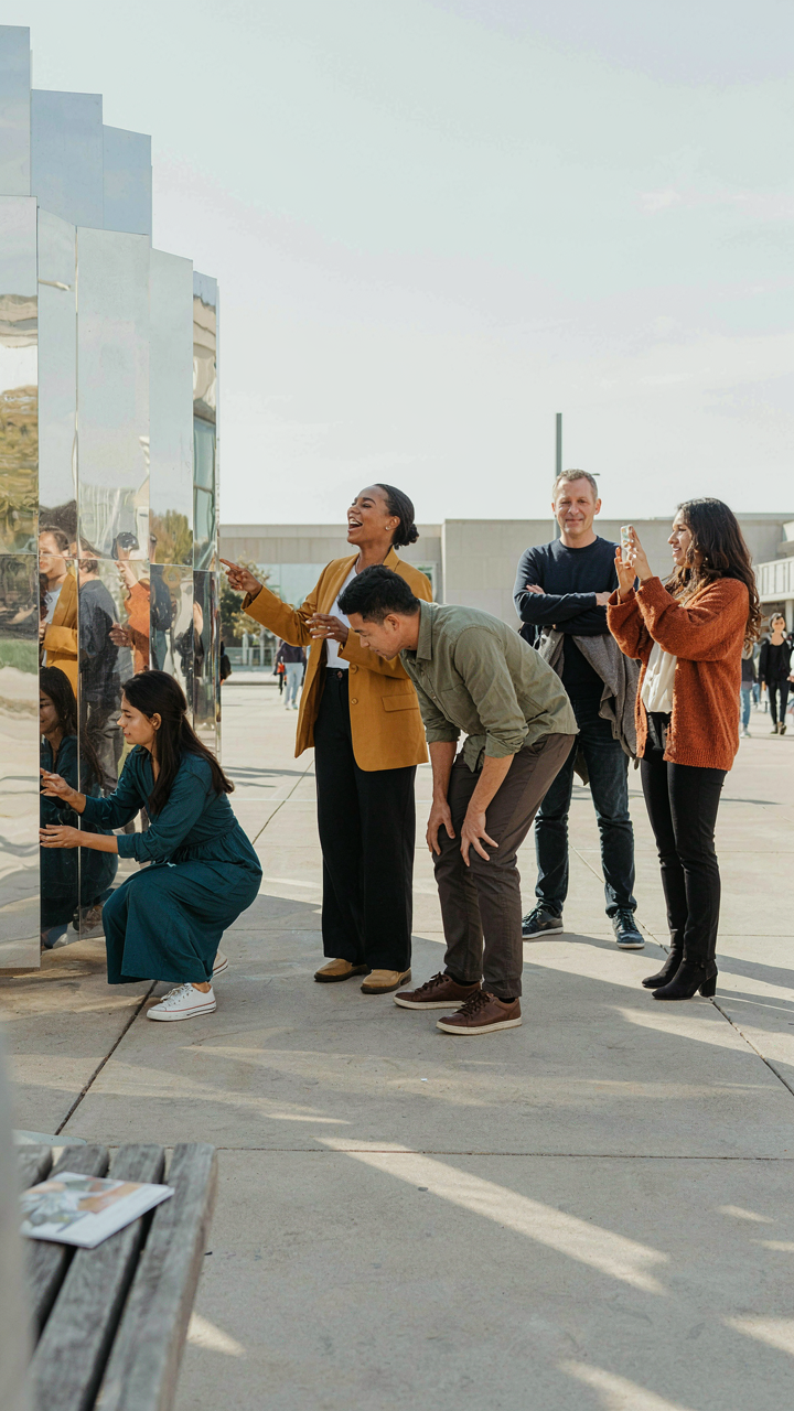 Adults engage and laugh at an immersive outdoor art installation, sharing a moment.