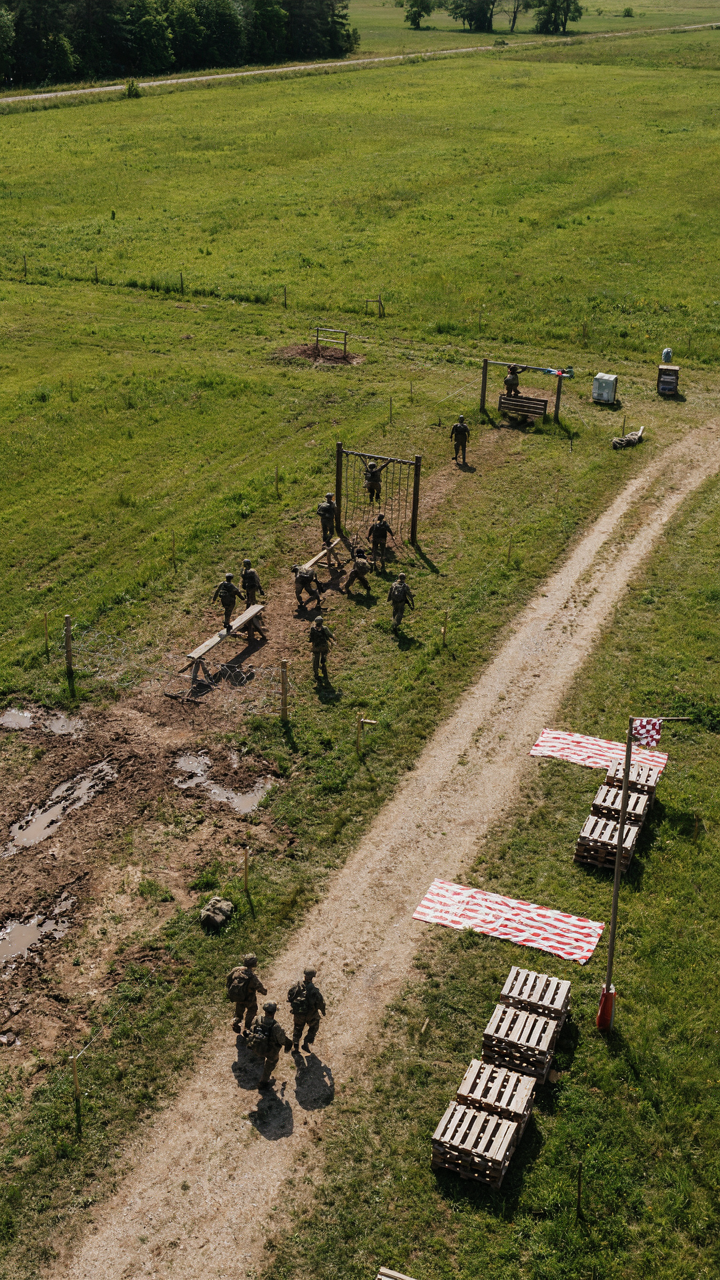 Soldiers navigate a complex outdoor obstacle course with clear paths.