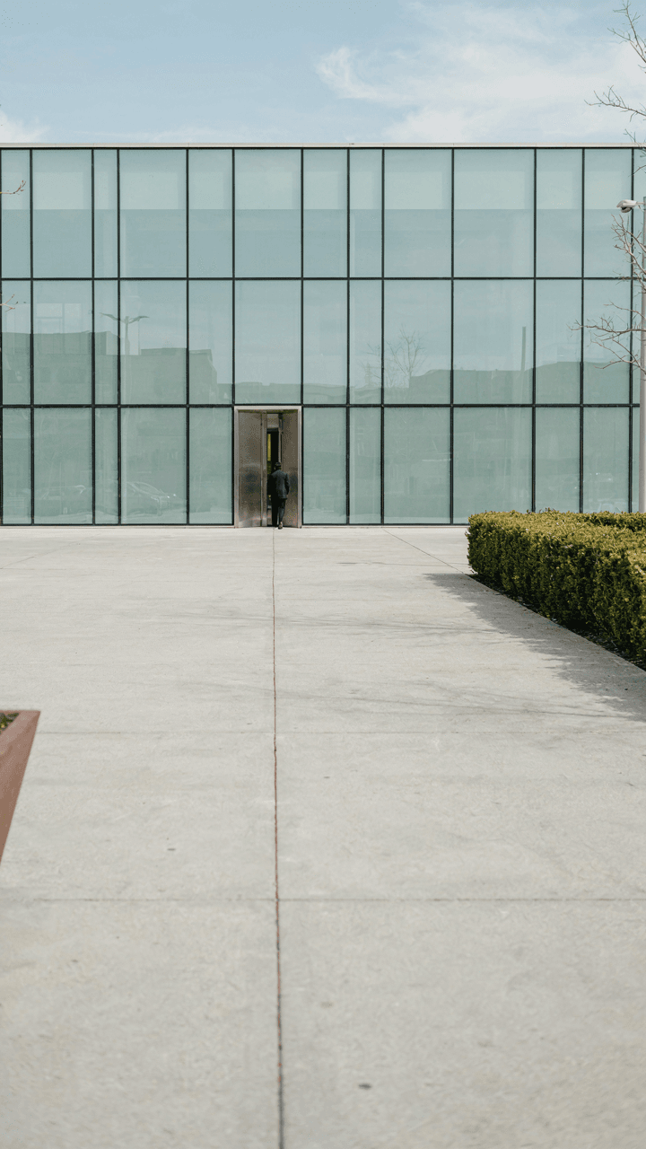 A very wide, smooth, empty sidewalk goes to a building.
