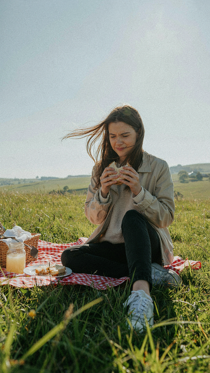 A woman shivers and squints uncomfortably at an outdoor picnic.