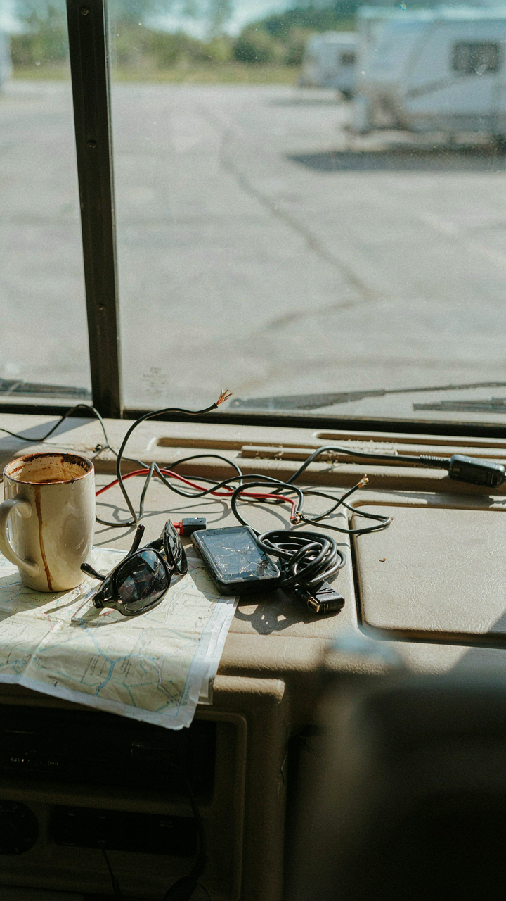 A cluttered RV dashboard filled with many electronic devices and tangled wires.